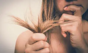 Mujer preocupada por su cabello seco y dañado. El alcohol bencílico puede ser un ingrediente útil para mejorar la salud del cabello.