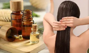 Aceite de romero para el pelo, aplicado en cabello largo y oscuro. Botellas de aceite y ramitas de romero al lado.