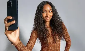 Mujer con cabello rizado oscuro toma selfie con iPhone. Muestra su estilo y los pasos del método curly.