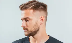 Hombre con un corte de pelo moderno, con un taper fade y raya marcada.