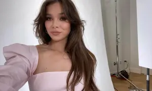 Mujer con cabello largo y castaño con un corte mariposa, luciendo un vestido rosa con mangas abullonadas.