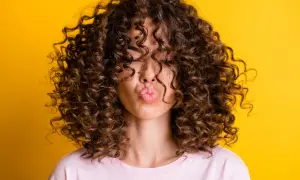 Chica con rizos perfectos, besando al aire. Su cabello luce espectacular gracias al método curlt.
