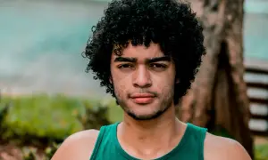 Hombre con cabello rizado y barba, luciendo un estilo natural que podría ser parte de un **método curly hombre**.
