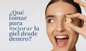 Mujer sonriente sostiene dos cápsulas amarillas, preguntándose qué tomar para mejorar la piel de la cara desde dentro.