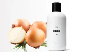 Champú de cebolla con propiedades beneficiosas para el cabello. Cebollas frescas y un frasco de champú blanco sobre fondo blanco.
