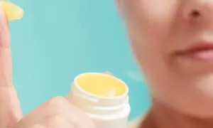 Dedo con vaselina amarilla, mostrando qué es el petrolatum. Un pequeño tarro blanco al lado.