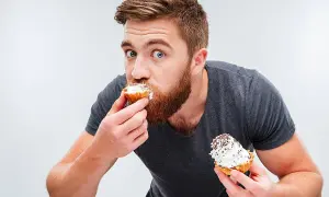 Hombre con barba comiendo pastelitos, ¿es esto un ejemplo de glicación?