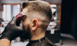 Barbero dando forma a un corte buzz cut fade con una máquina.