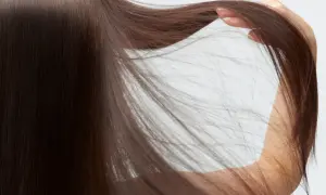 Cabello castaño oscuro y sedoso, con una mano acariciando las puntas. Descubre cómo cuidar el pelo fino para lograr este aspecto.