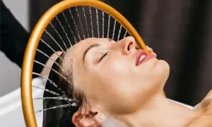 Mujer disfrutando de un relajante spa para cabello con agua cayendo sobre su rostro.