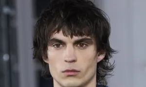 Hombre joven con un moderno mullet corto, cabello oscuro y despeinado, mirada intensa.