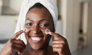 Sonrisa radiante con crema en mejillas, anticipando los resultados de retinol antes y después.
