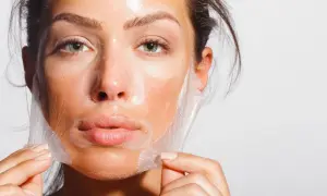 Mujer retirando una mascarilla de su rostro, un paso clave para como alisar la piel de la cara y lograr un cutis radiante.