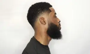 Hombre con un corte de pelo con tuper fade y barba cuidada, perfilado impecable.