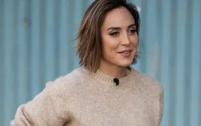 Mujer con un moderno corte bob con flequillo, luciendo un suéter beige y una sonrisa amable.