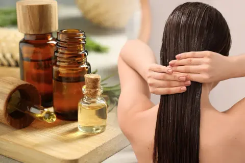 Aceite de romero para el pelo, aplicado en cabello largo y oscuro. Botellas de aceite y ramitas de romero al lado.