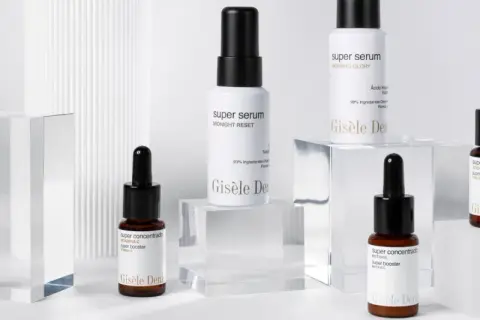 Varios frascos de sérum y super booster de Gisèle Denis, con etiquetas que detallan sus ingredientes y beneficios.