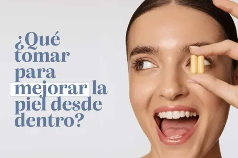 Mujer sonriente sostiene dos cápsulas amarillas, preguntándose qué tomar para mejorar la piel de la cara desde dentro.