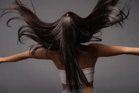 Cabello oscuro y sedoso moviéndose con gracia. Descubre qué es la taninoplastia y cómo puede transformar tu melena.