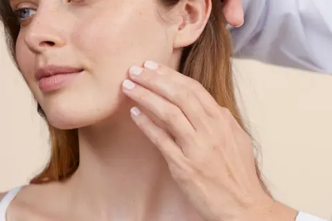 Una mano acaricia suavemente el rostro de una mujer, sugiriendo cómo desmaquillarse sin desmaquillante, con una piel radiante y natural.