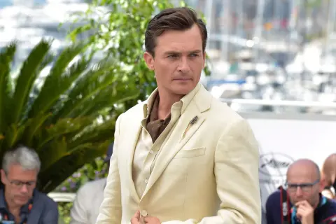 Hombre con un impecable corte de pelo old money, viste un traje de lino color crema y un pañuelo de seda.