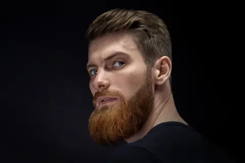 Hombre con barba y cortes de pelo hombre elegante, mirada intensa.