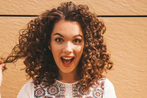 Mujer con cabello rizado y voluminoso, que parece que no le gusta que le apelmacen el cabello.