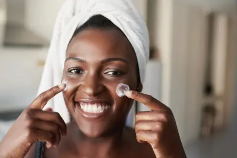 Sonrisa radiante con crema en mejillas, anticipando los resultados de retinol antes y después.