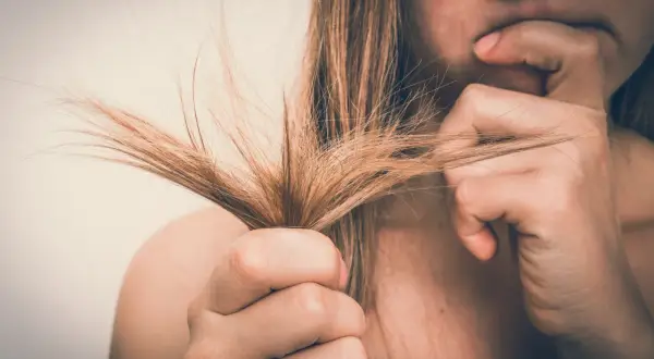 Mujer preocupada por su cabello seco y dañado. El alcohol bencílico puede ser un ingrediente útil para mejorar la salud del cabello.