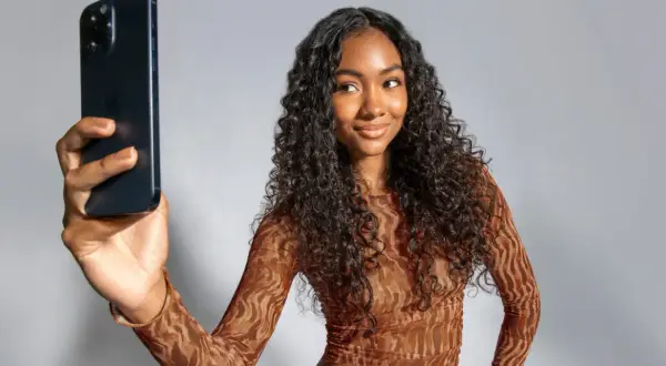 Mujer con cabello rizado oscuro toma selfie con iPhone. Muestra su estilo y los pasos del método curly.