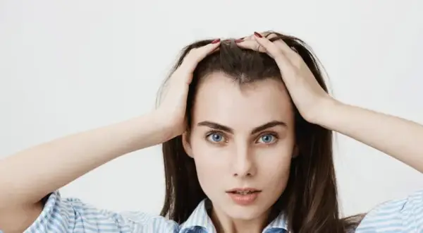 Mujer con las manos en la cabeza, mostrando sus baby hairs y ojos azules intensos.
