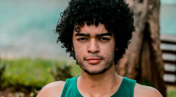 Hombre con cabello rizado y barba, luciendo un estilo natural que podría ser parte de un **método curly hombre**.