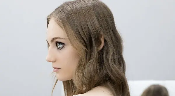 Perfil de mujer con media melena escalada y maquillaje artístico en los ojos.