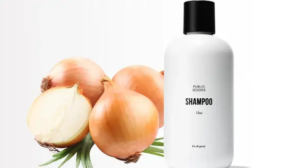 Champú de cebolla con propiedades beneficiosas para el cabello. Cebollas frescas y un frasco de champú blanco sobre fondo blanco.