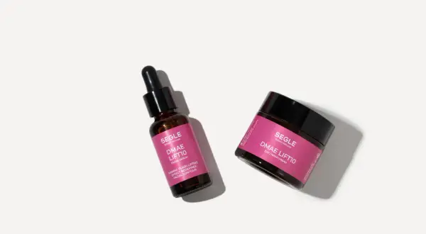 Un frasco de suero facial y un tarro de crema DMAE Lift10 de Segle, para una piel firme y redefinida.