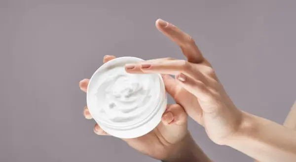 Manos aplicando crema hidratante. La urea en las cremas ayuda a retener la humedad, dejando la piel suave.