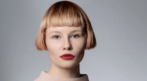 Mujer con pelo corto con flequillo desfilado, ojos azules y labios rojos.