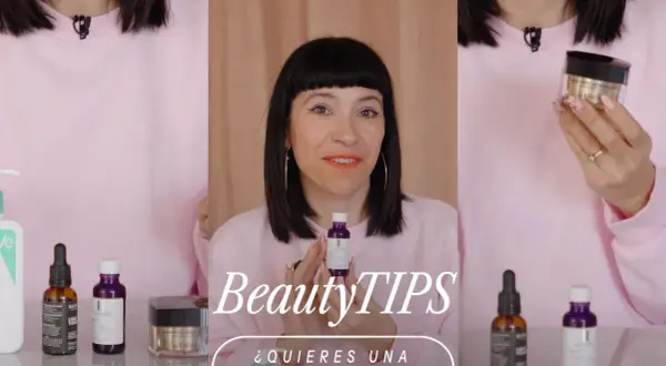 Mujer con maquillaje vibrante y un suéter rosa muestra productos de belleza, buscando un efecto glow cara.