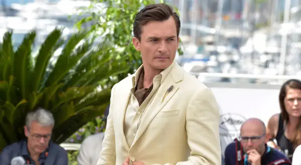 Hombre con un impecable corte de pelo old money, viste un traje de lino color crema y un pañuelo de seda.