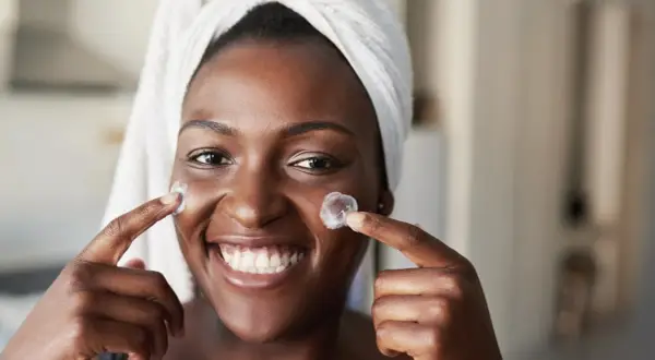 Sonrisa radiante con crema en mejillas, anticipando los resultados de retinol antes y después.