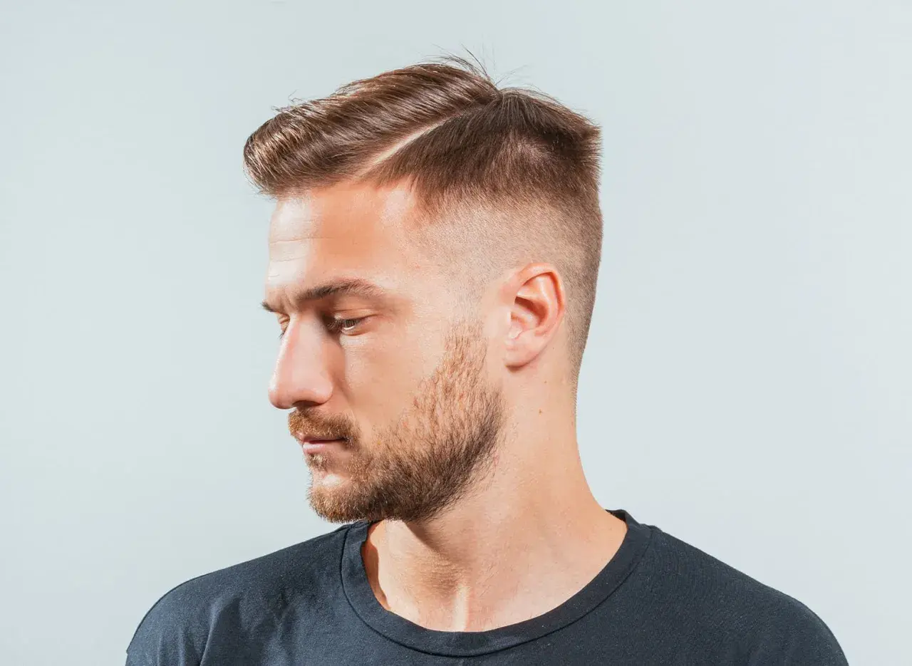 Hombre con un corte de pelo moderno, con un taper fade y raya marcada.