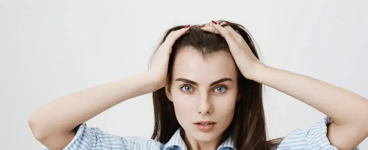 Mujer con las manos en la cabeza, mostrando sus baby hairs y ojos azules intensos.