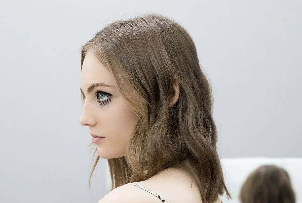 Perfil de mujer con media melena escalada y maquillaje artístico en los ojos.
