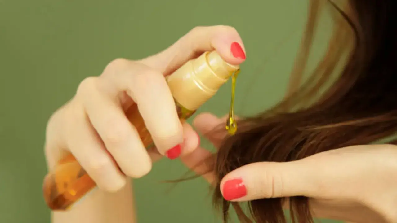 Mano aplica aceite capilar, un producto común en cosmética por sus siliconas, para dar brillo y suavidad al cabello.