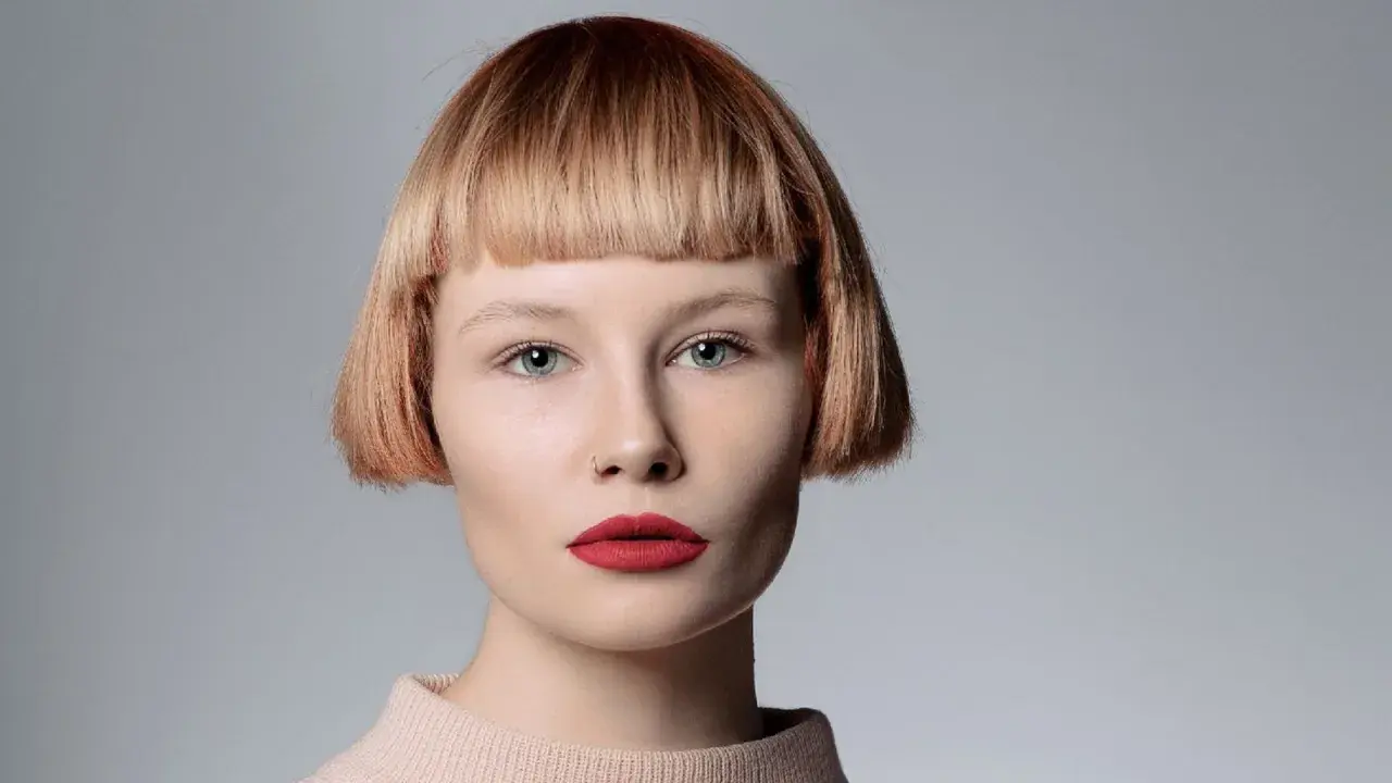 Mujer con pelo corto con flequillo desfilado, ojos azules y labios rojos.