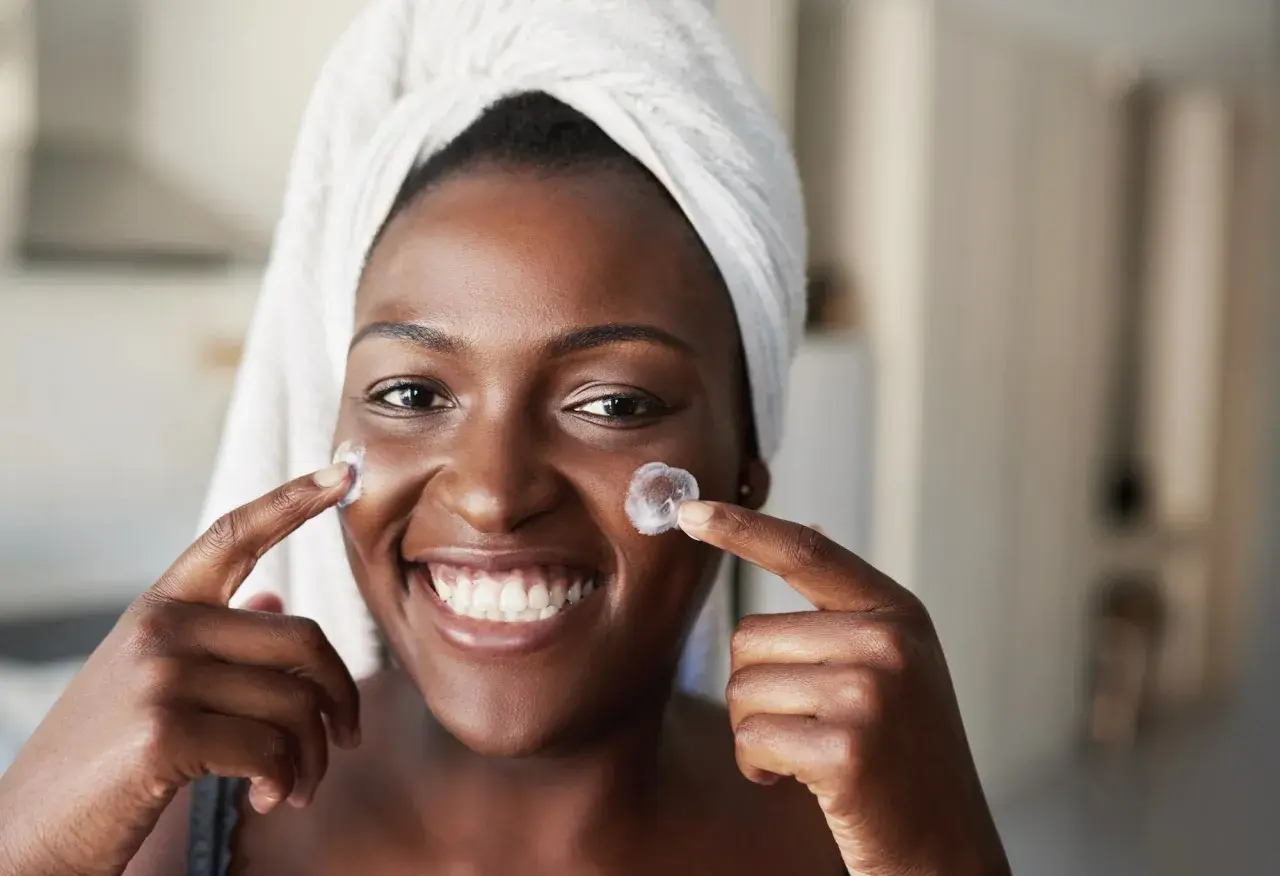 Sonrisa radiante con crema en mejillas, anticipando los resultados de retinol antes y después.