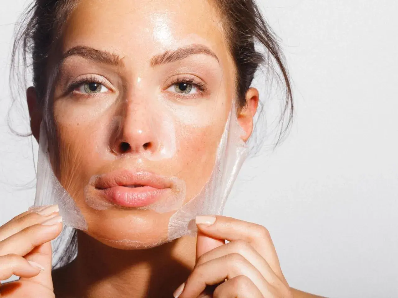 Mujer retirando una mascarilla de su rostro, un paso clave para como alisar la piel de la cara y lograr un cutis radiante.