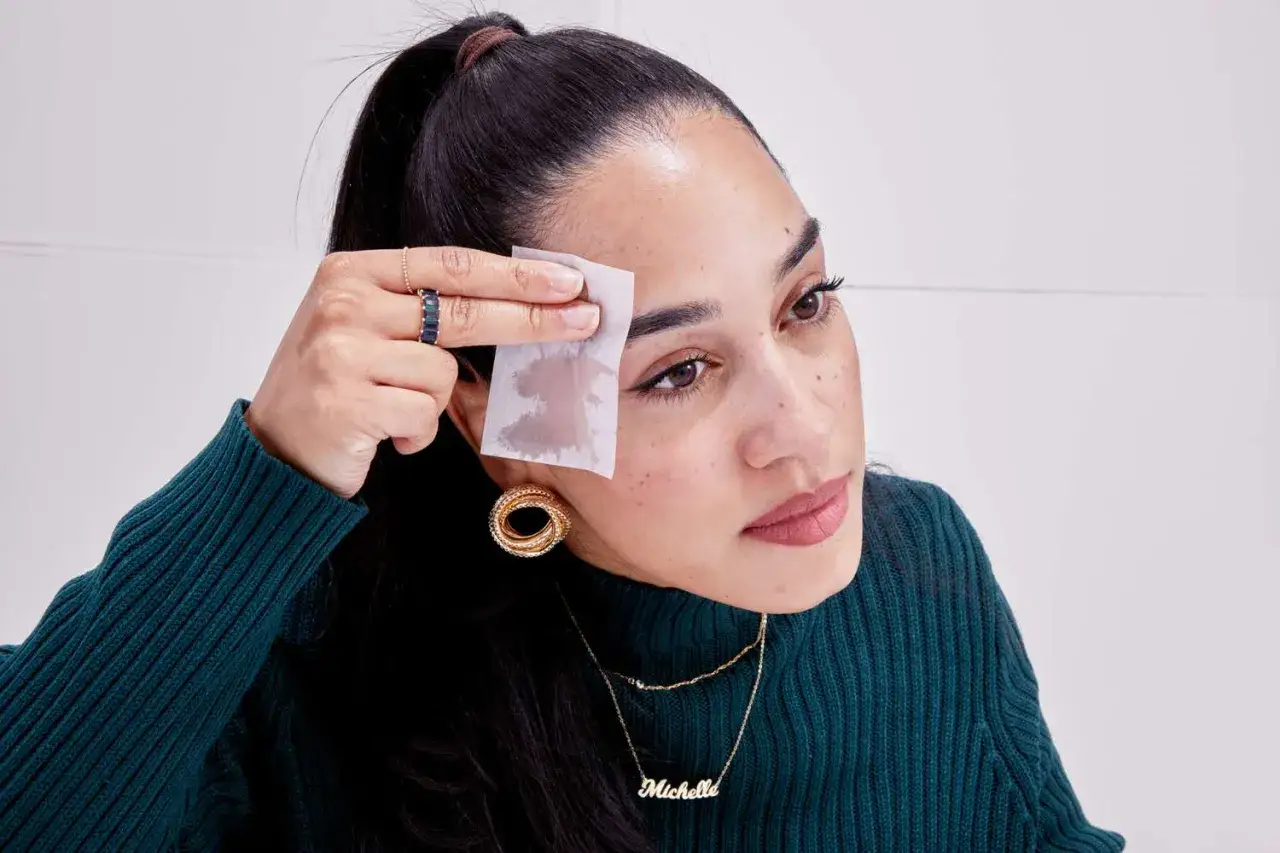 Mujer se limpia la frente con una toallita para saber si tienes piel grasa. La toallita absorbe el brillo.