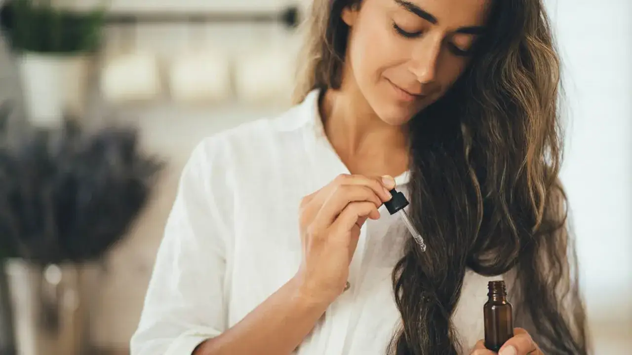 Mujer aplicando aceite en su pelo seco y encrespado.