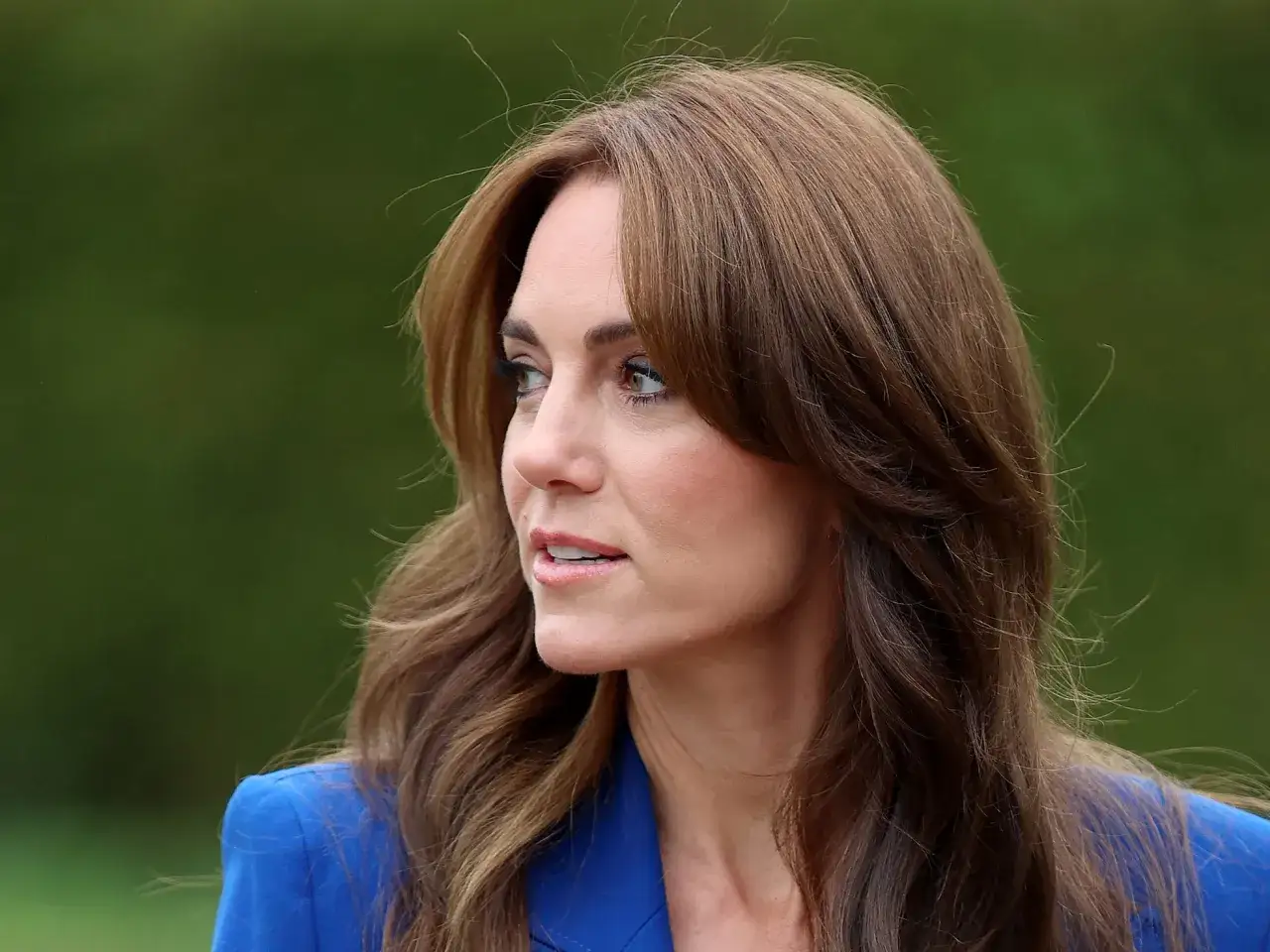 Mujer con cabello castaño y flequillo mariposa, luciendo un blazer azul.